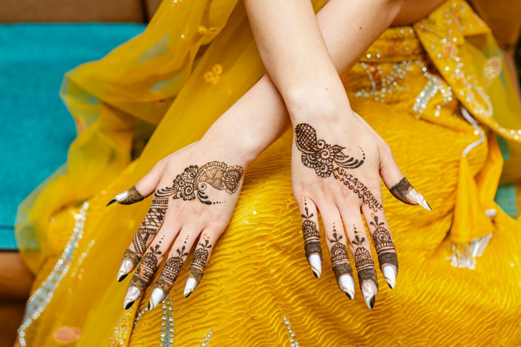 Close-up of intricate mehndi designs on hands wearing a yellow sari in Kathmandu, Nepal.