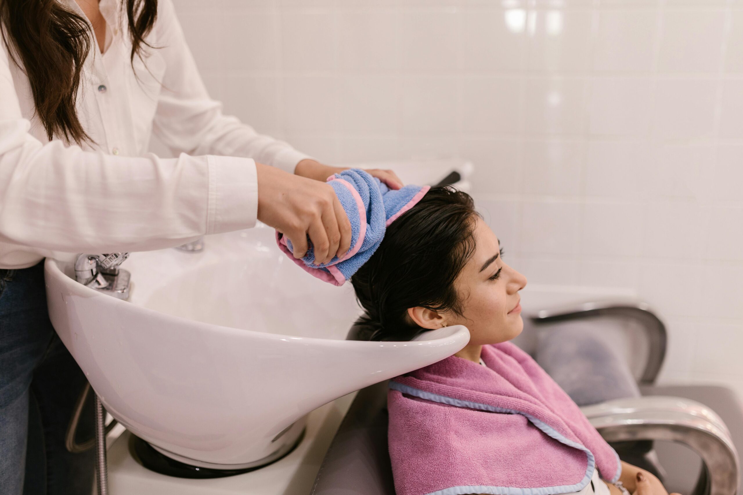 A woman enjoys a relaxing hair wash at a modern hair salon, emphasizing self-care and pampering.